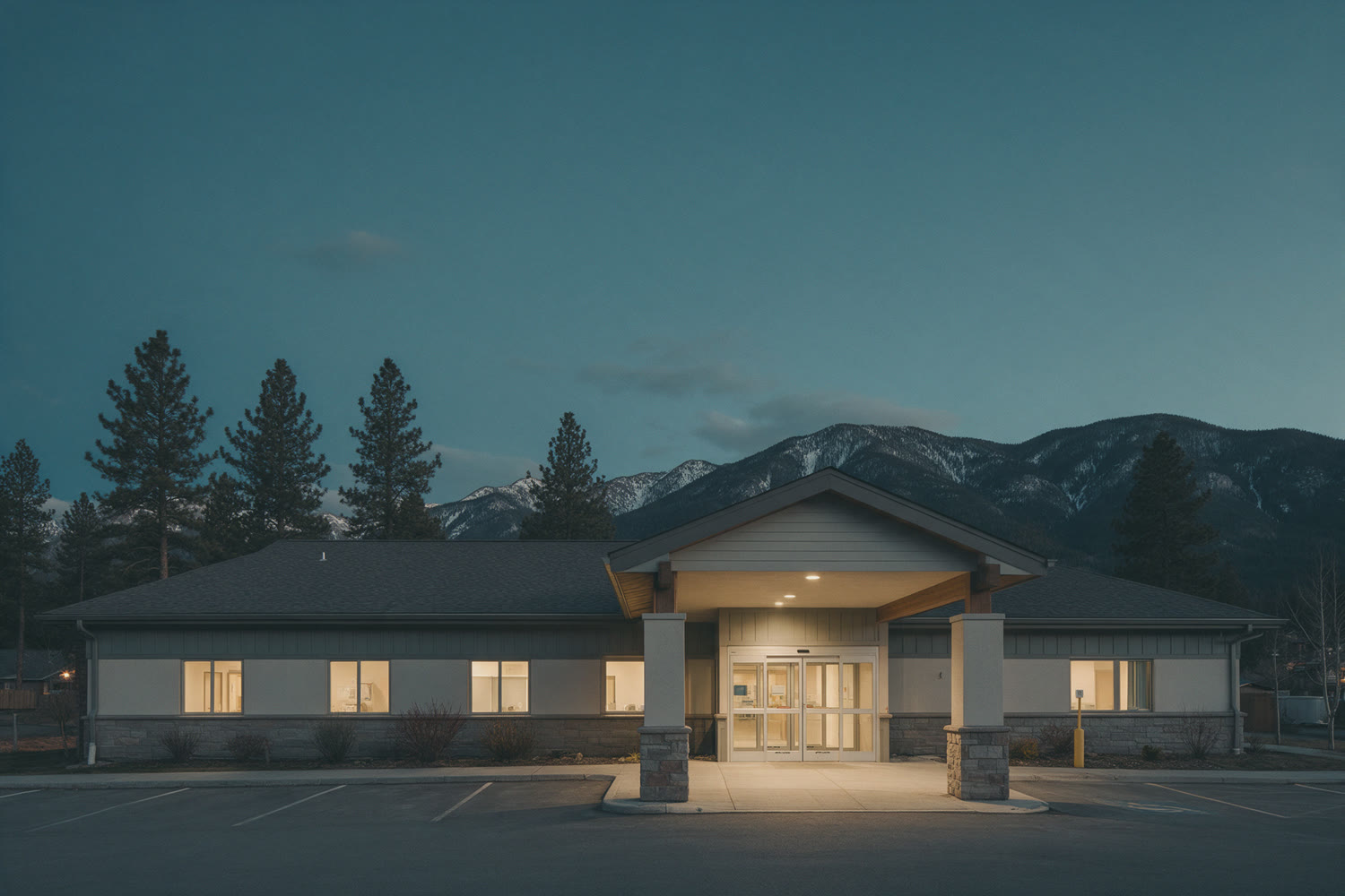 A small rural hospital at dusk with mountains behind it